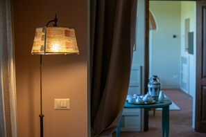Ein Zimmer mit Stehlampe, Lichtschalter und Tisch mit Laterne.