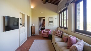 Ein Wohnzimmer mit einer Couch, einem Fernseher, einem Kamin und einem Fenster mit Vorhängen.