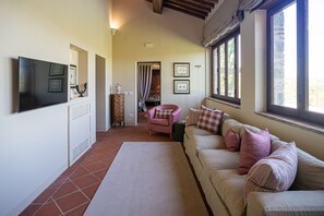 Ein Wohnzimmer mit einer Couch, einem Fernseher, einem Kamin und einem Fenster mit Vorhängen.
