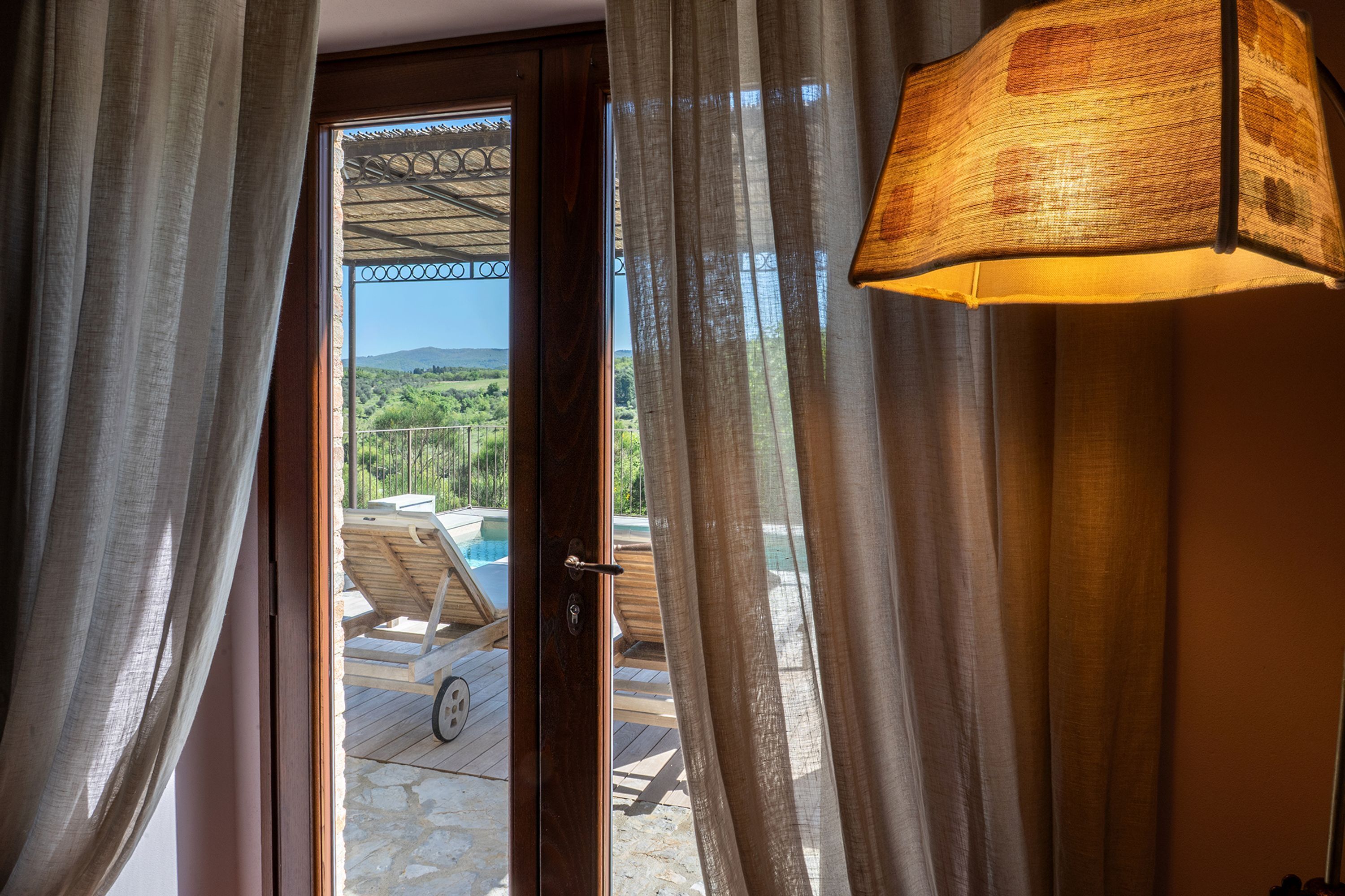 A doorway with a view of a pool area, a wooden deck, and a mountainous landscape.