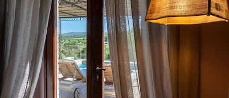 A doorway with a view of a pool area, a wooden deck, and a mountainous landscape.