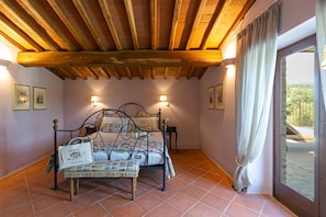 A bedroom with a wooden ceiling, a bed with a metal frame, two wall-mounted lights, and a window with curtains. - Casa Faraona Villa With Private Pool (Gaiole in Chianti)