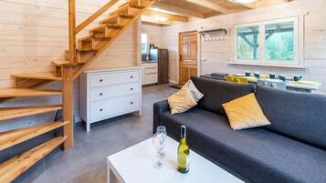 A wooden interior with a sofa, a dining table, and a staircase.