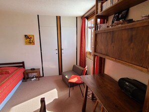 A bedroom with a bed, a desk, a chair, a bookshelf, and a radiator. - Functional apartment, bright view - 4 guests (La Plagne)