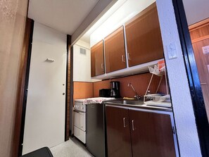 A compact kitchen with a stove, oven, and sink, featuring wooden cabinets and a coffee maker. - Functional apartment, bright view - 4 guests (La Plagne)