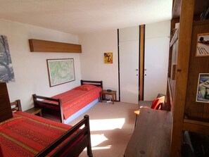 A small, compact room with a single bed, a small table, and a wardrobe. - Functional apartment, bright view - 4 guests (La Plagne)