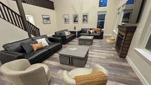 Ein modernes Wohnzimmer mit Kamin, Ledersofas und einer Treppe.