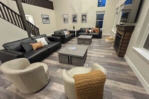 Ein modernes Wohnzimmer mit Kamin, Ledersofas und einer Treppe.