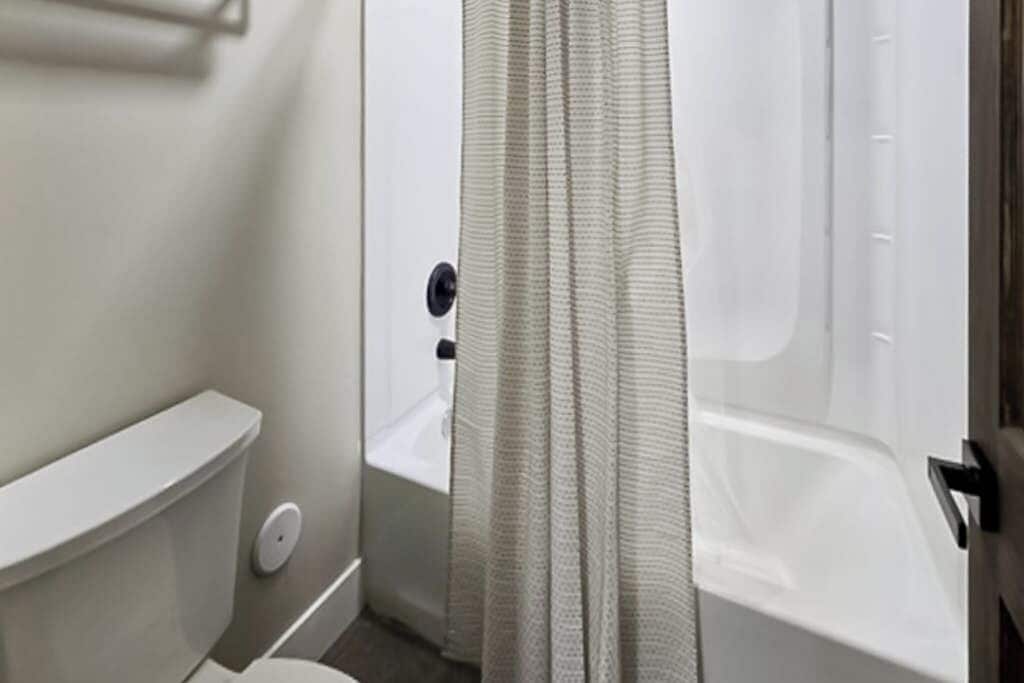Et badeværelse med toilet, badekar og bruseforhæng.