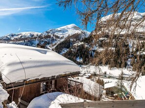 Eine verschneite Berglandschaft mit einer Holzhütte und einem strahlend blauen Himmel.