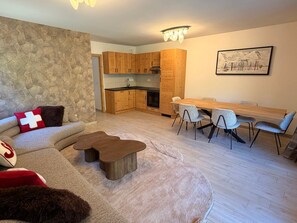 Een moderne woonkamer met een bank, een salontafel en een eethoek met stoelen en een tafel.