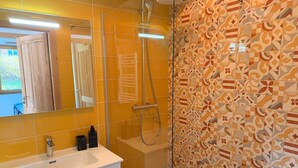 Un baño con ducha, lavamanos y espejo.