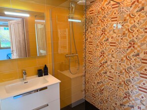 Ein Badezimmer mit Dusche, Waschbecken und Spiegel.