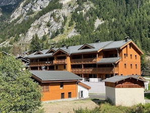Eine mehrstöckige Holzlodge mit Balkonen vor einer Bergkulisse.