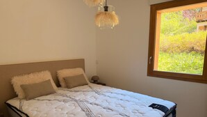 Una cama con colchón blanco, dos almohadas y cabecero.