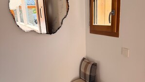 Una habitación con un banco de madera, un espejo adosado a la pared y un ventanal de madera.