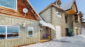 A two-story house with a stone facade, a wooden deck, and a garage.