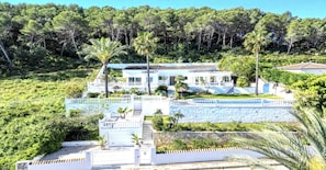 A large, multi-story house with a white exterior, surrounded by lush greenery and palm trees. - Villa in Xabia, Splendid View and Pool (Javea)