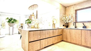 A modern kitchen with wooden cabinetry, a built-in sink, and a large window. - Villa in Xabia, Splendid View and Pool (Javea)