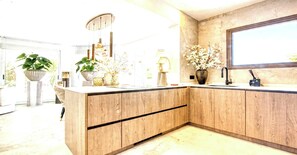 A modern kitchen with wooden cabinetry, a built-in sink, and a large window. - Villa in Xabia, Splendid View and Pool (Javea)