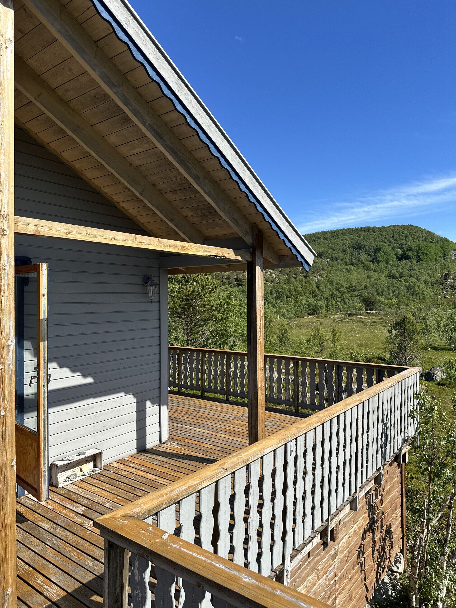 A wooden deck with a railing overlooking a green landscape.
