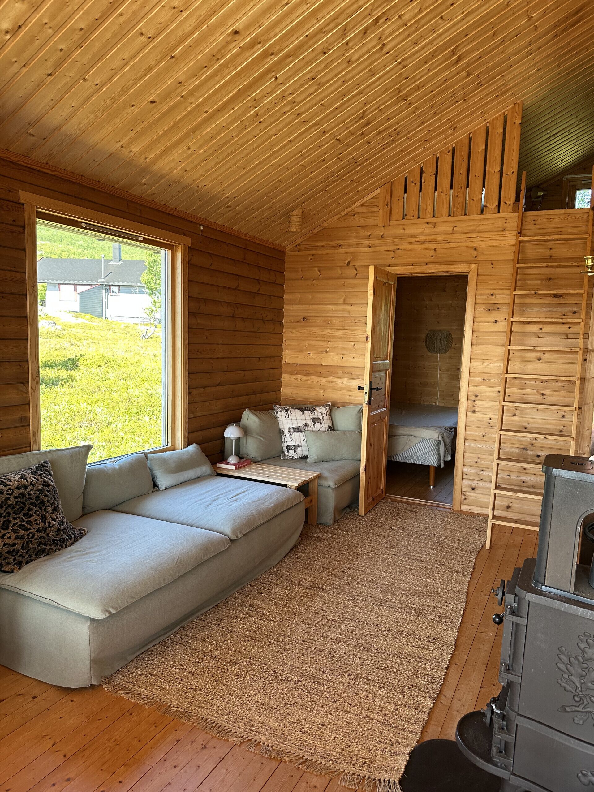 Et hyggeligt interiør i en hytte med en sofa, et lille bord og en pejs.