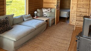 A cozy cabin interior with a sofa, a small table, and a fireplace.