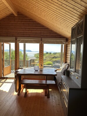 Una terraza de madera con una mesa y bancos, con vistas a un paisaje pintoresco.