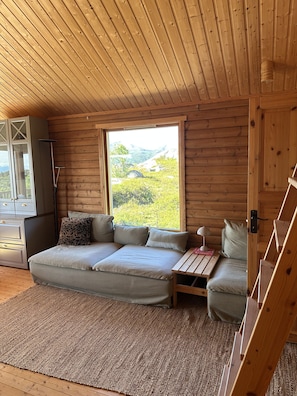 Un interior de madera con sofá, una mesita y vistas al exterior.