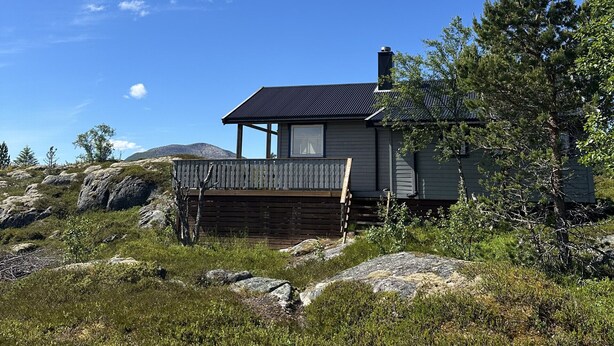 A house with a deck, surrounded by rocks and vegetation.
