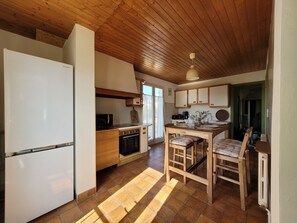 Une cuisine de taille réduite équipée d’un réfrigérateur, d’un four, d’un four à micro-ondes et de meubles de rangement en bois.