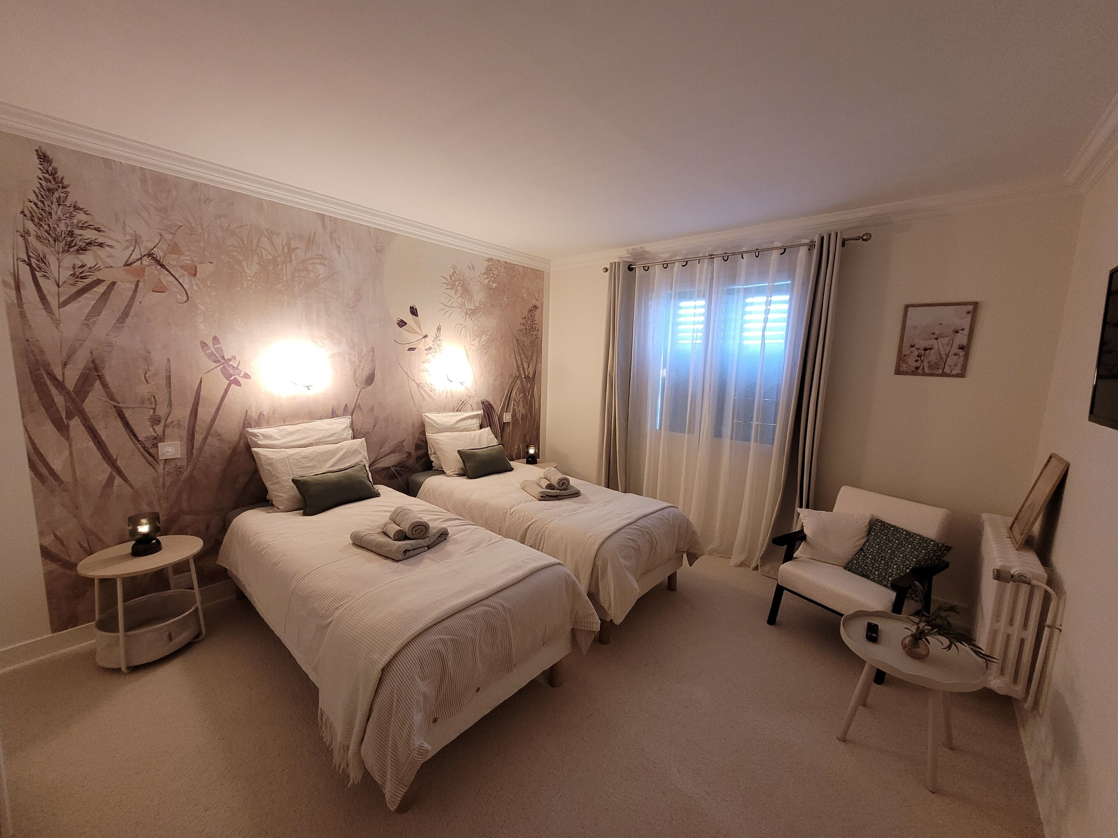 Een hotelkamer met twee bedden, een zithoek en een wand met een natuurdecoratie.