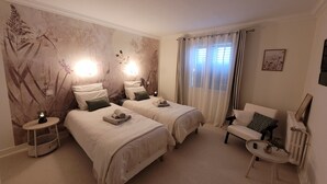 A hotel room with two beds, a sitting area, and a wall with a nature-themed mural. - Gîte des Tulipes de Bray (Neufchâtel-en-Bray)