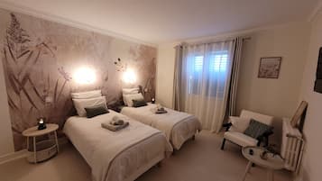 Een hotelkamer met twee bedden, een zithoek en een wand met een natuurdecoratie.