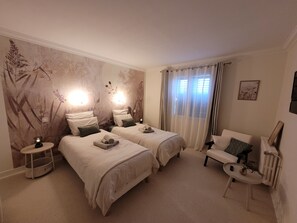 Habitación de hotel con dos camas, zona de estar y un mural temático de naturaleza.