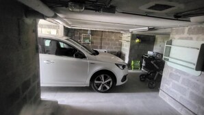 A white car parked in a garage with a stroller and a baby carrier. - Gîte des Tulipes de Bray (Neufchâtel-en-Bray)