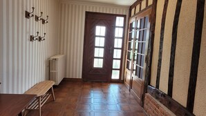 A hallway with a wooden bench, a radiator, and a door with windows. - Gîte des Tulipes de Bray (Neufchâtel-en-Bray)