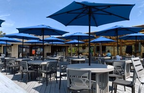 Terrasse mit runden Tischen und blauen Sonnenschirmen.