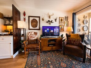 Ein Wohnzimmer mit einer Holzeinrichtungsanlage, einem gemusterten Teppich und verschiedenen Wanddekorationen, darunter Tierkopfskulpturen und gerahmte Kunstwerke.