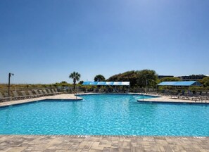 A swimming pool with lounge chairs and umbrellas, surrounded by a tiled deck. - Ocean Villas A246-Professionally Managed by HHIB&T Vacation Rentals (Hilton Head Island)