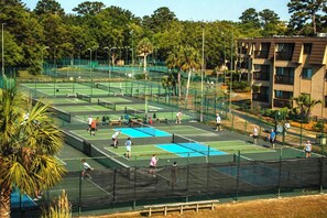 Ein Tennisplatzkomplex mit mehreren Plätzen, umgeben von Bäumen und einem Wohngebäude.