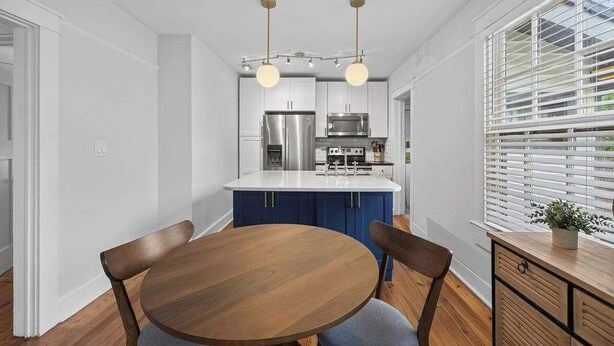 Een moderne keuken met witte kasten, roestvrijstalen apparatuur en een centraal kookeiland met een spoelbak.