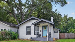 Een gelijkvloers huis met veranda, schoorsteen en een blauwe deur.