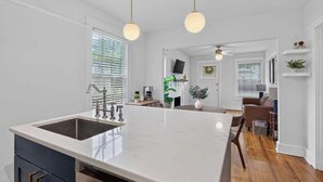 Een keuken met een groot eiland, een inbouwgootsteen en hanglampen.
