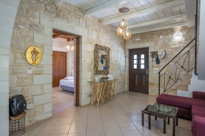 A stone-walled room with a bed, a glass table, and a staircase. - Villa Freedom | A Private Luxury Estate in the Heart of Crete (Chania)
