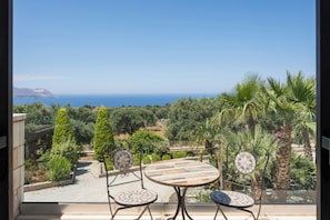 A balcony with a view of the sea, a table, and chairs. - Villa Freedom | A Private Luxury Estate in the Heart of Crete (Chania)