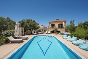 A swimming pool with lounge chairs and a stone building with a tiled roof. - Villa Freedom | A Private Luxury Estate in the Heart of Crete (Chania)