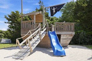 A wooden play structure with a slide and stairs. - Coral Cay - Oceanside home (Emerald Isle)