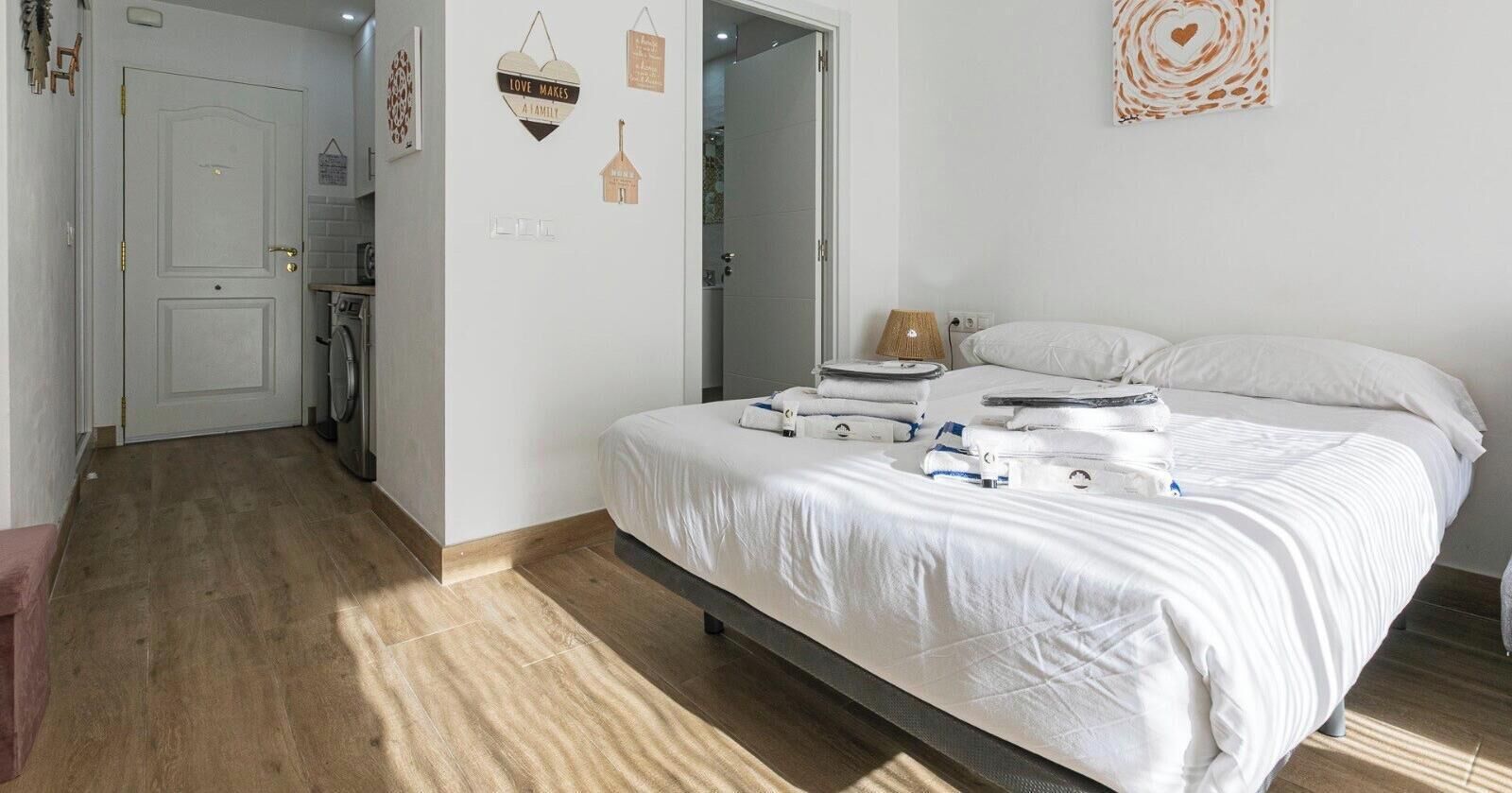 Un dormitorio con una cama, una lámpara de noche y una pared decorada.