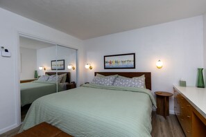 A hotel room with a bed, bedside tables, a dresser, a mirror, and a painting on the wall. - Bay View Dunes Getaway (North Bend)